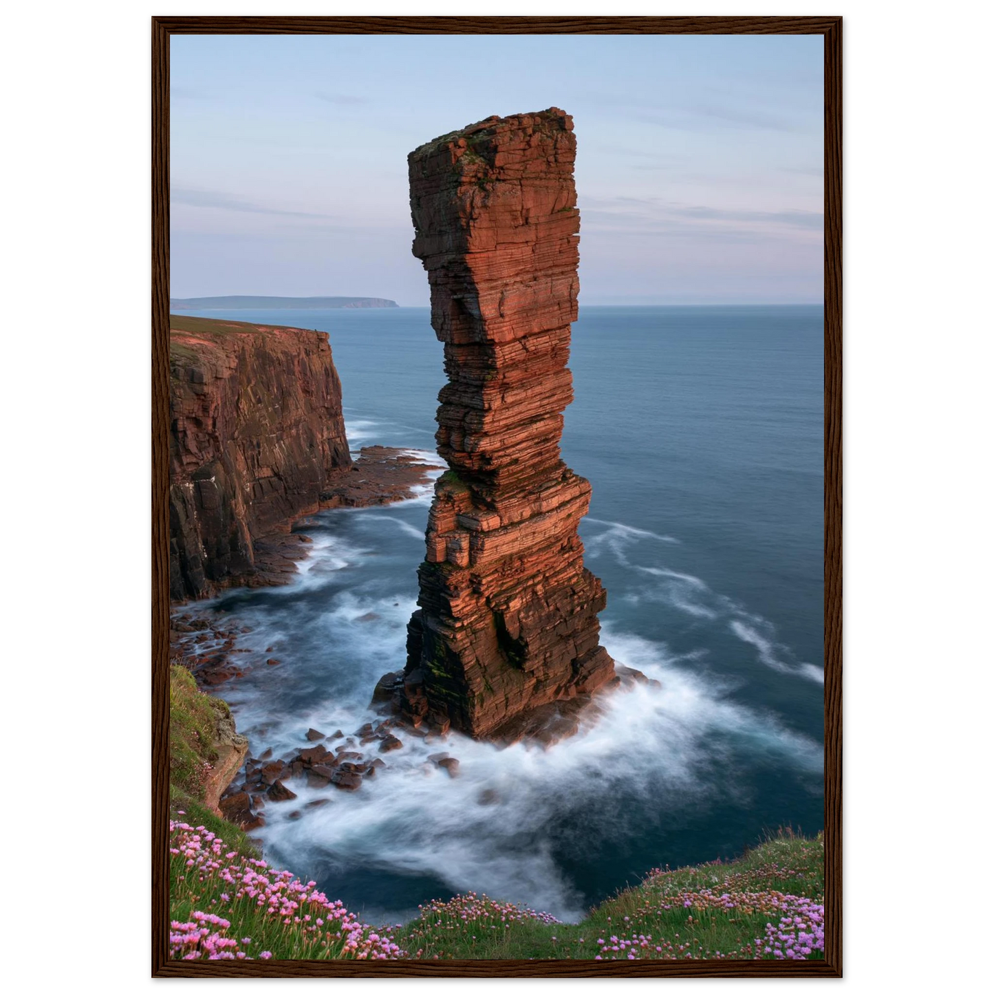 Red sandstone sea stack at last light above an Atlantic cliff coast, print in a dark brown wood frame