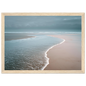 Quiet beach and shallow surf under a grey sky, framed in light natural wood