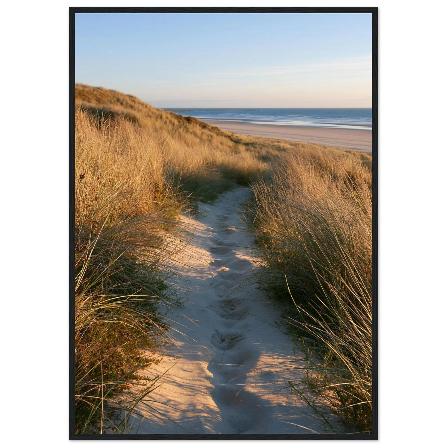 Sand track through amber marram grass to an empty beach at golden hour, print in a black frame