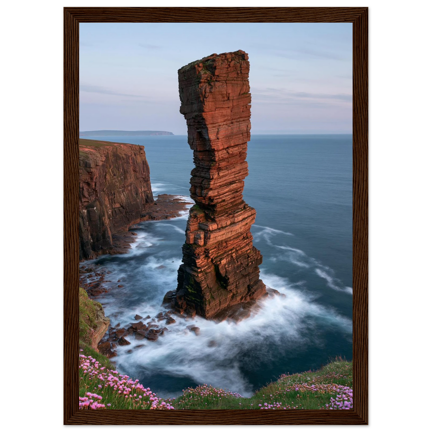 Red sandstone sea stack at last light above an Atlantic cliff coast, print in a dark brown wood frame