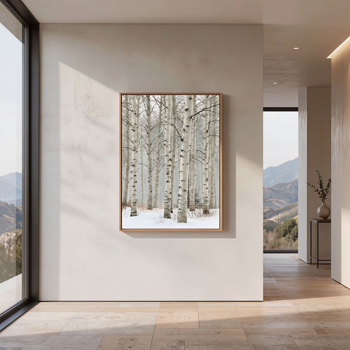 Birch in falling snow, in a pale wood frame on a bare plaster wall in a minimalist hallway with a mountain view