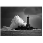 A wave bursting white over a lone stone lighthouse on a dark reef in a heavy sea, black and white, print in a slim dark frame