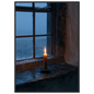 Candle burning on a stone windowsill at blue dusk, print in a black frame