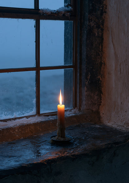 A single lit candle on a deep stone windowsill seen from inside a dark room, snow falling in the blue dusk beyond the glass