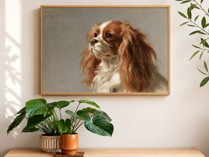 A Blenheim Cavalier King Charles Spaniel oil portrait in a wood frame, hanging above a console table with houseplants