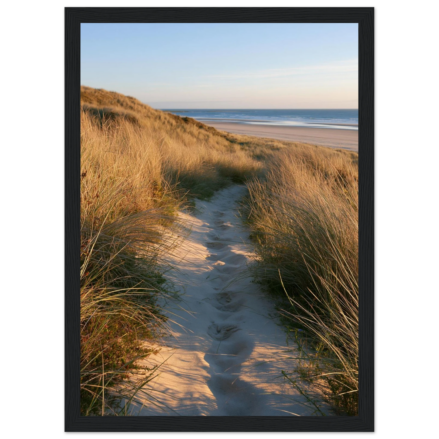 Sand track through amber marram grass to an empty beach at golden hour, print in a black frame