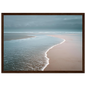 Wet sand and shallow water under low cloud, framed in warm dark wood