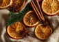 Dried orange slices, cinnamon sticks, star anise and a sprig of spruce arranged on crumpled natural linen, seen from directly above