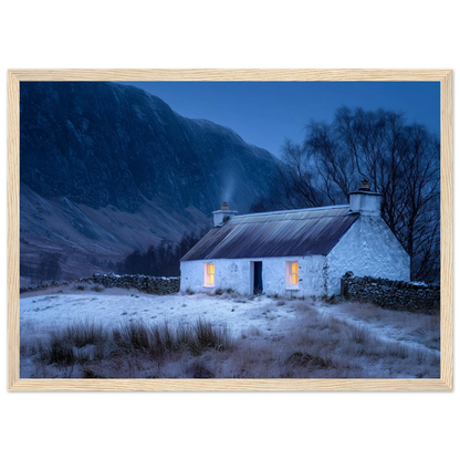 Highland cottage with lit windows in winter, print in a pale natural wood frame