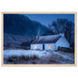 Highland cottage with lit windows in winter, print in a pale natural wood frame