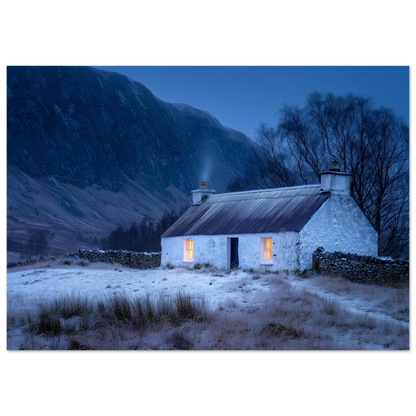 A whitewashed Highland croft with two lit windows at blue winter dusk, smoke from the chimney, drystone wall and snow-dusted mountain behind, in a slim dark frame