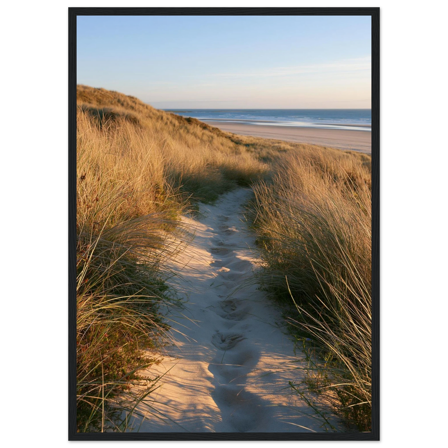 Sand track through amber marram grass to an empty beach at golden hour, print in a black frame