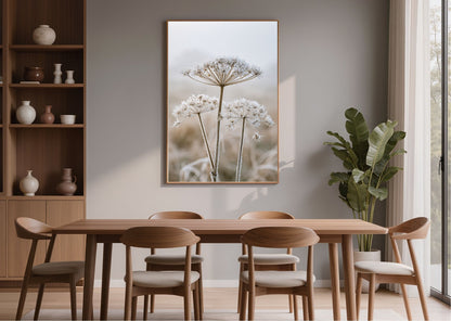 Frosted seedhead print in a wood frame above a wooden dining table in a bright dining room