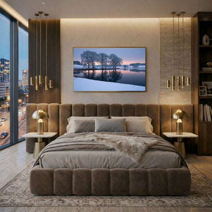 Frozen lake print in a gold frame above a bed in a warm modern city bedroom