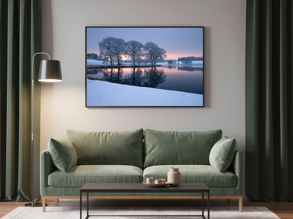 Frozen lake print in a dark frame above a sage green sofa in a living room