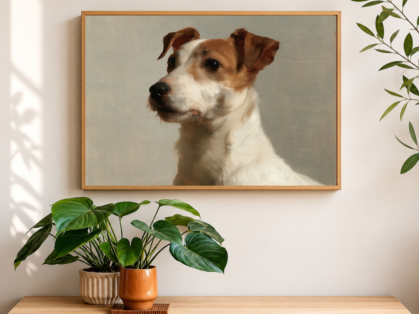 A Jack Russell terrier oil portrait in a wood frame, hanging above a console table with houseplants