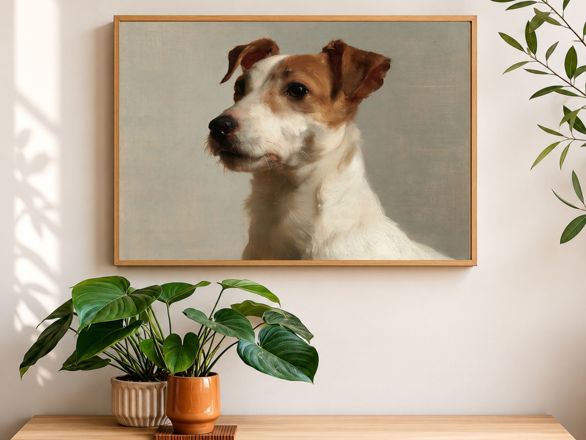 A Jack Russell terrier oil portrait in a wood frame, hanging above a console table with houseplants