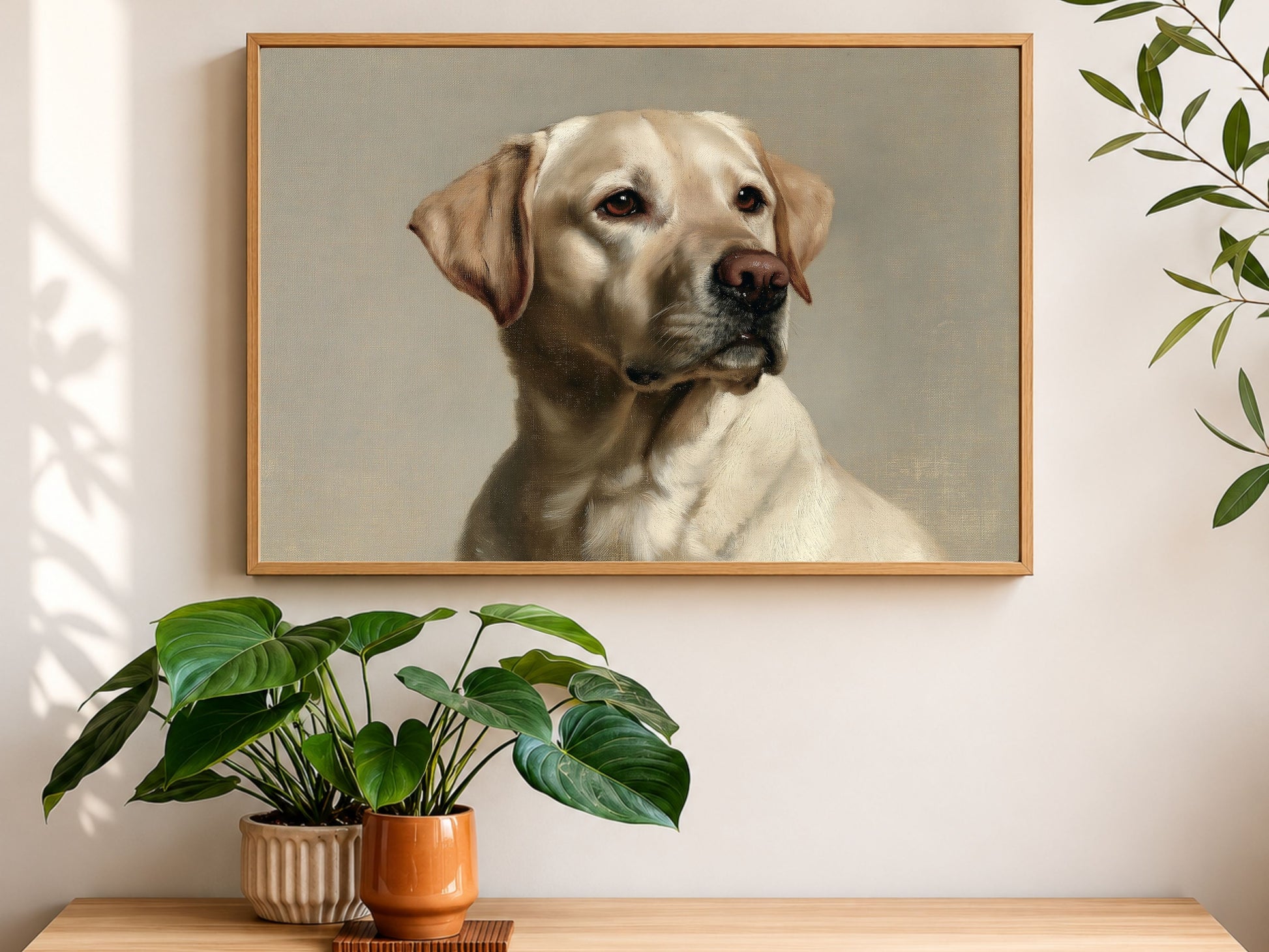 A yellow Labrador Retriever oil portrait in a wood frame, hanging above a console table with houseplants