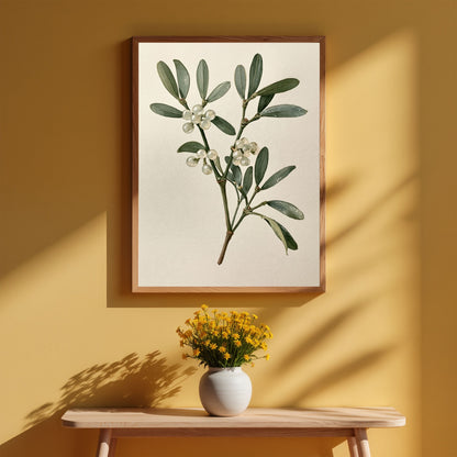 Mistletoe sprig with white berries, in a light wood frame on a warm ochre wall above a small wooden table