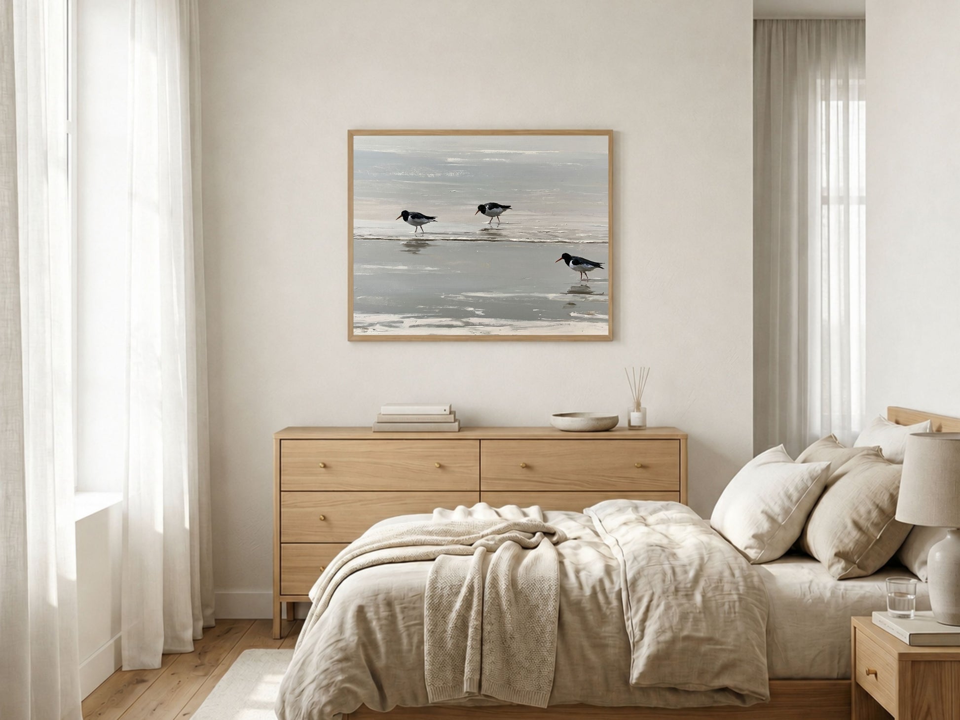 Three oystercatchers on the tideline, framed in light wood above an oak sideboard in a calm neutral bedroom