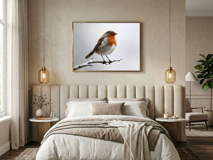 Robin on a snowy branch print in a wood frame above a bed in a warm neutral bedroom