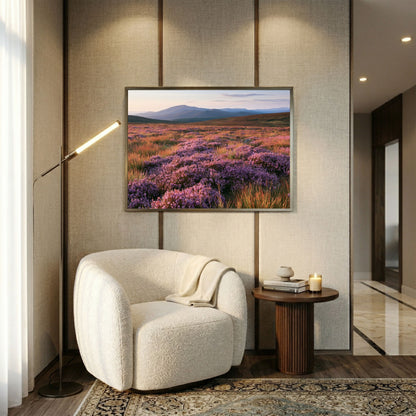 Purple heather moor below blue hills, print in a slim pewter frame above a cream boucle armchair in a linen panelled reading corner