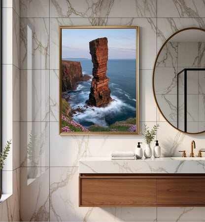 Red sandstone sea stack at last light, framed in gold above a marble vanity in a bathroom