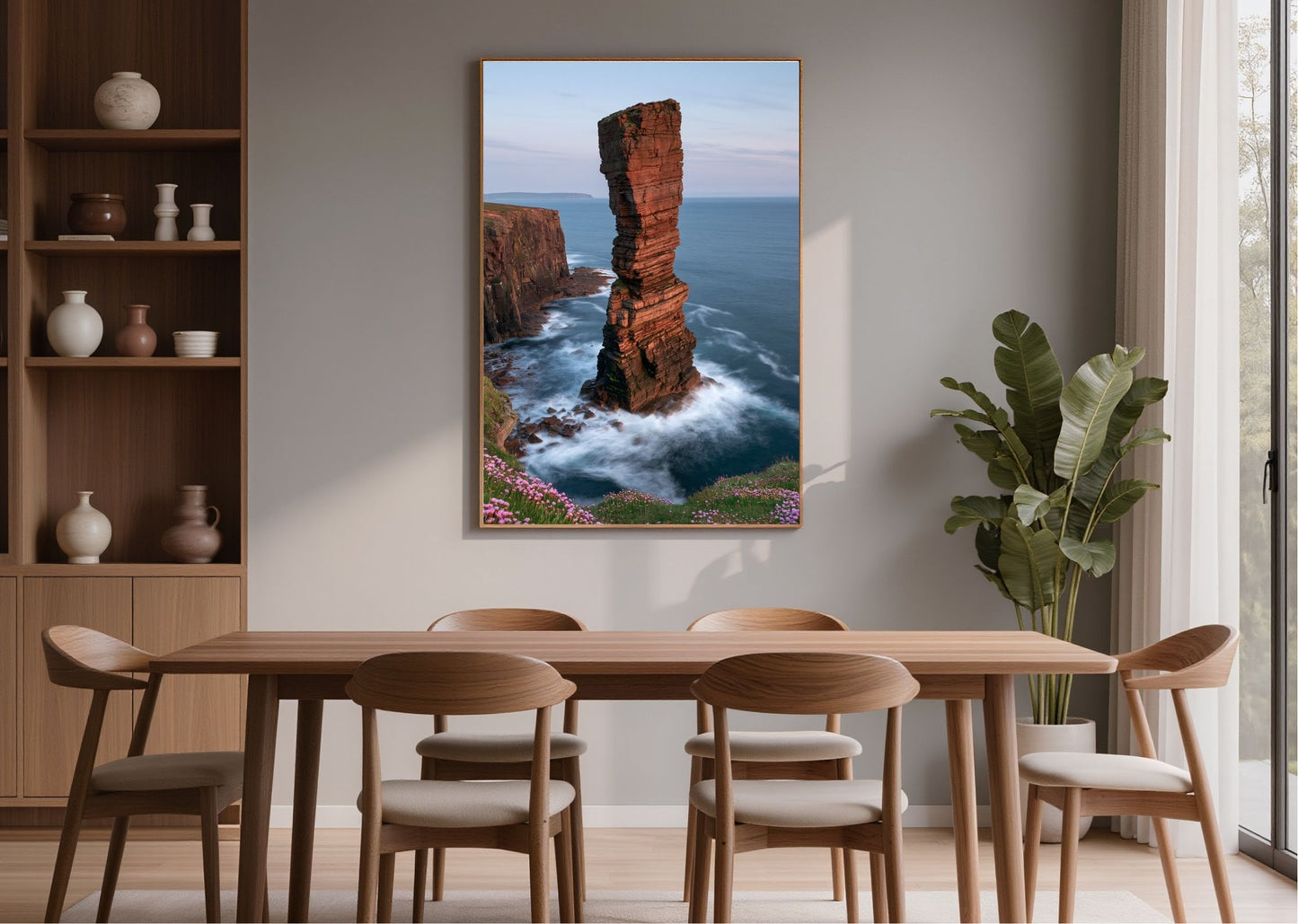 Red sandstone sea stack at last light, framed in light wood above a dining table beside open shelving