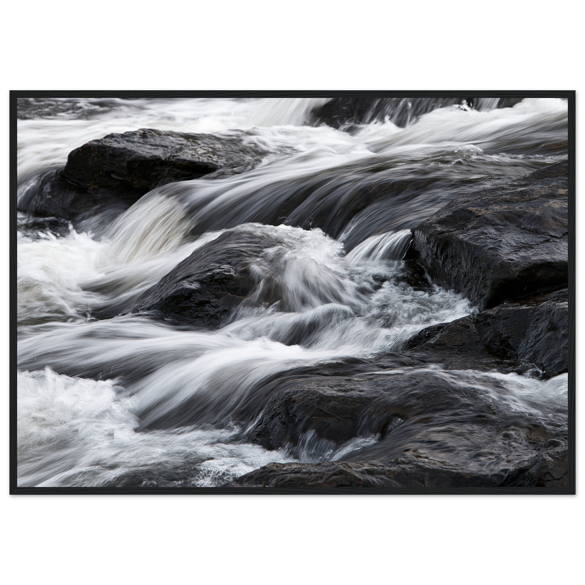 Silk water over dark rock, print in a black frame