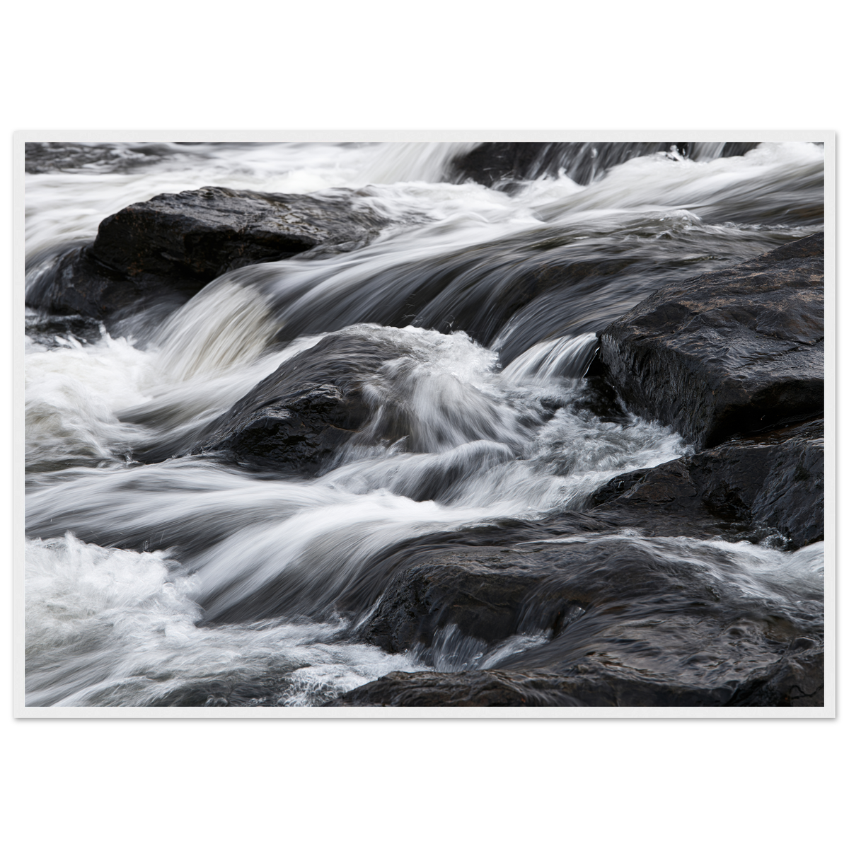 Silk water over dark rock, print in a white frame