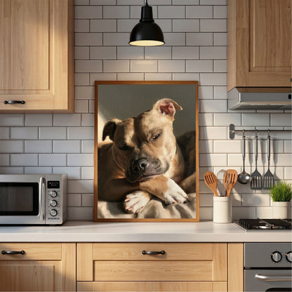 Staffordshire bull terrier at rest, in a light wood frame standing on the worktop of a white subway-tiled kitchen
