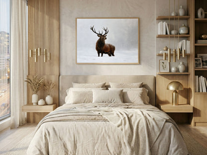 Red deer stag in falling snow print in a light wood frame above a bed in a calm neutral bedroom