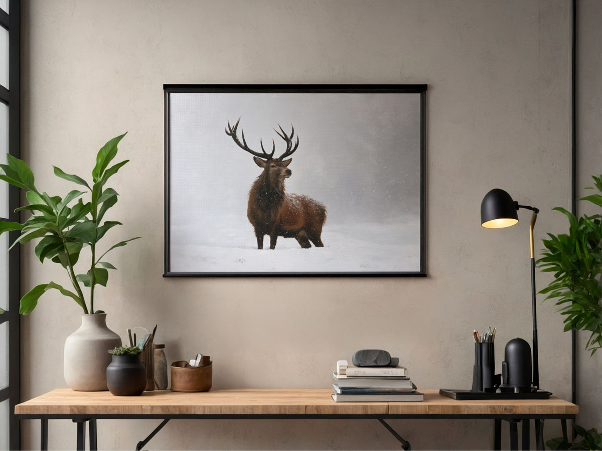 Red deer stag in falling snow print in a black frame above a slim desk in a modern home office