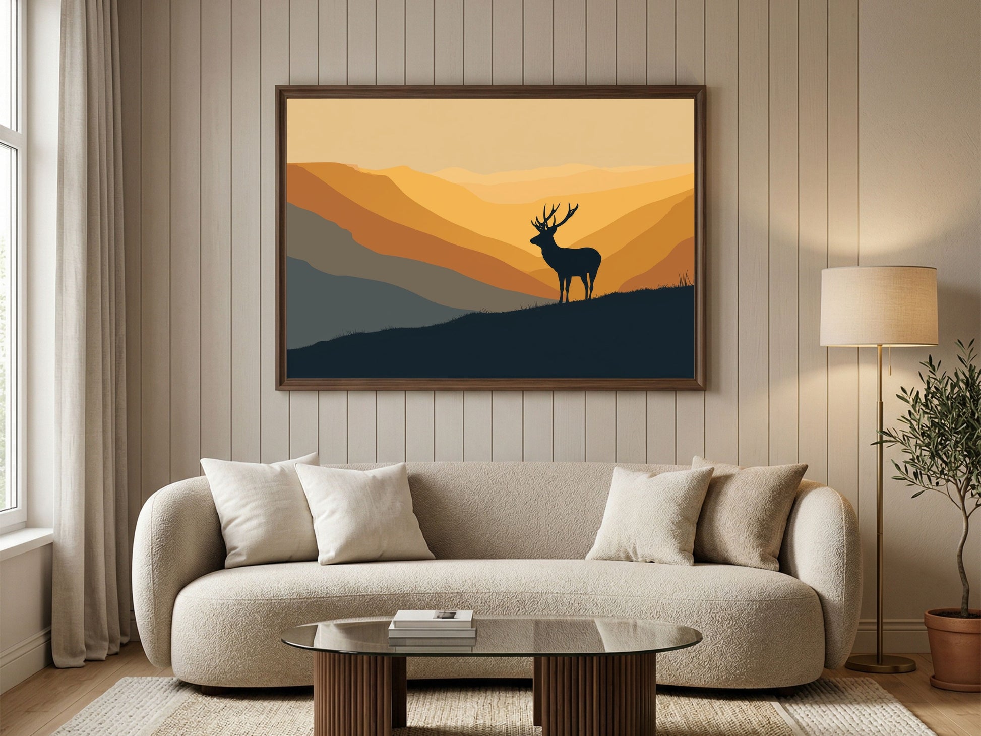 Stag silhouette on a ridge at amber dawn, framed in wood above a cream boucle sofa in a bright living room