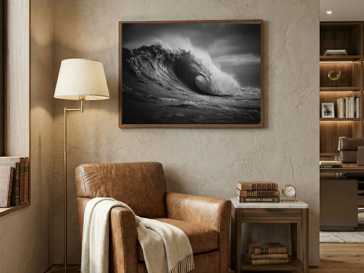 Black and white barrelling ocean wave, framed above a leather armchair in a warm living room