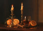 A candlelit still life of brass candlesticks, clove-studded oranges, cinnamon and a glass of whisky on dark polished wood