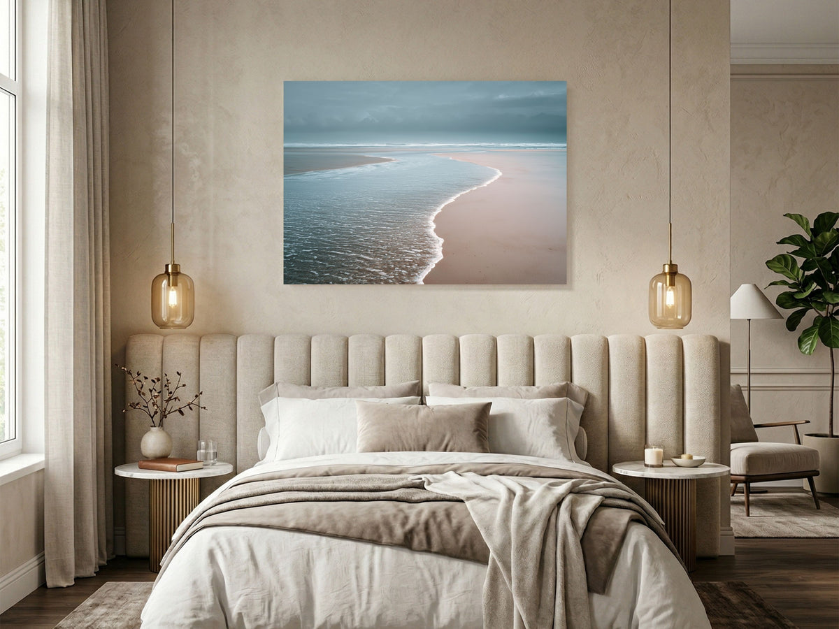 Pale sea washing over an empty beach at low tide, hanging above a bed in a soft neutral bedroom