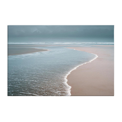 A thin sheet of water sliding back over wet sand at the tide line under a low grey sky, pink-grey sand meeting blue-green shallows, printed on stretched canvas